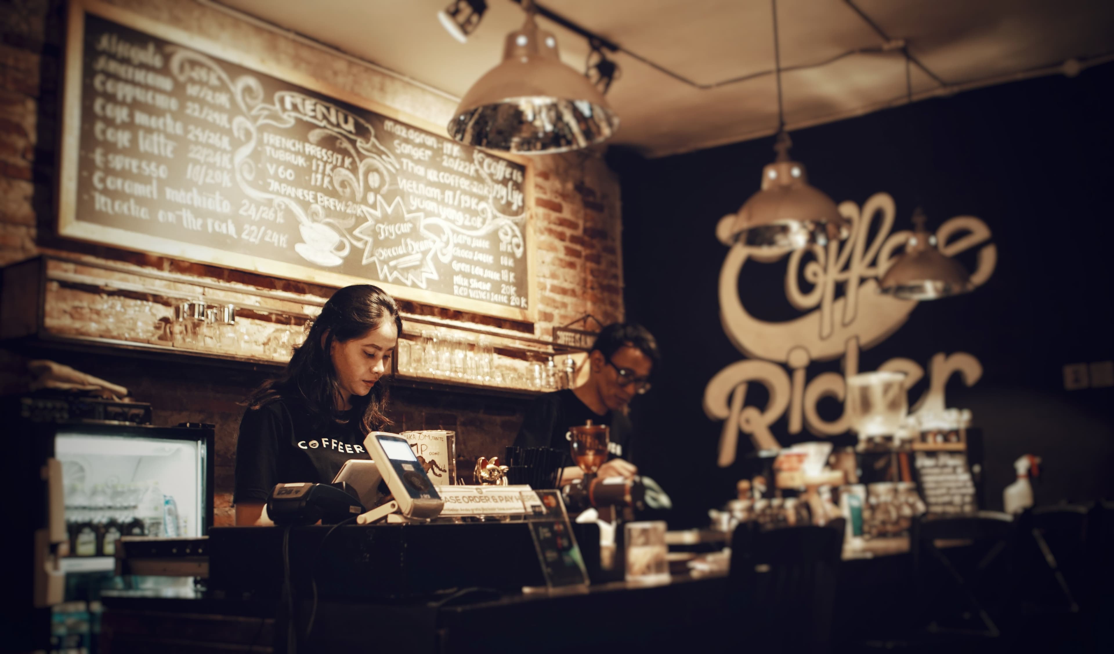 A barista and colleague working behind the counter of a coffee shop