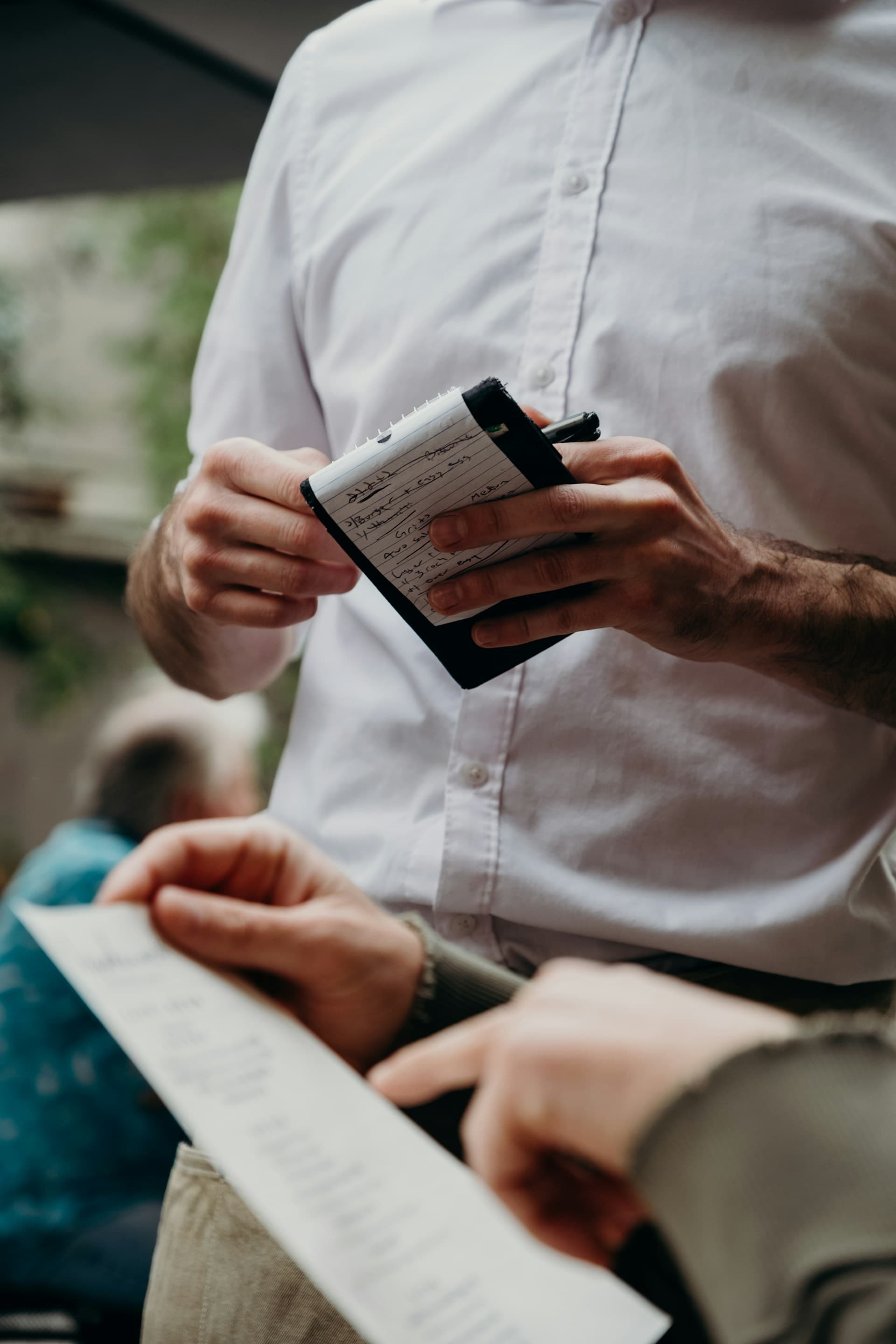 A server noting a guest's order and dietary requests by hand